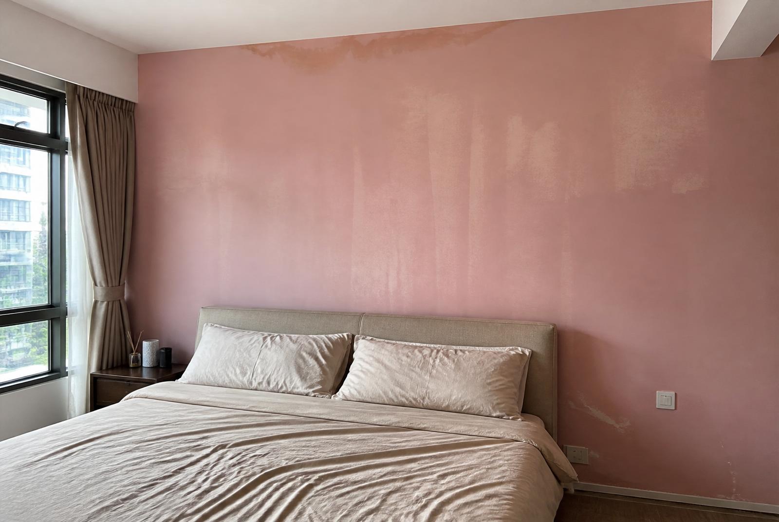 Condo bedroom with dated patchy dusty-pink feature wall before repaint